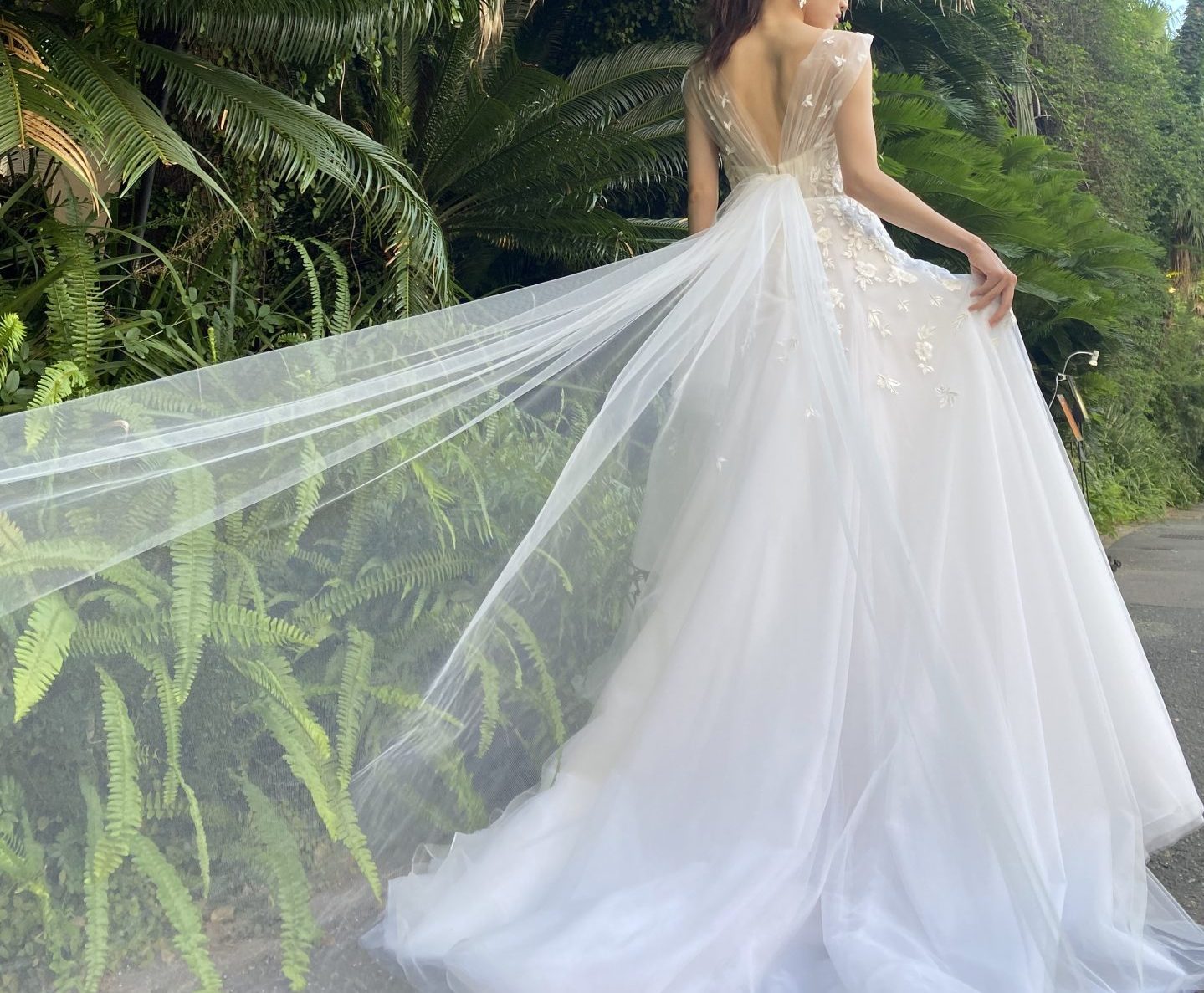 バックリボンの繊細で柔らかなチュールが風になびき、ルイガンズ花嫁におすすめの新作ウェディングドレス