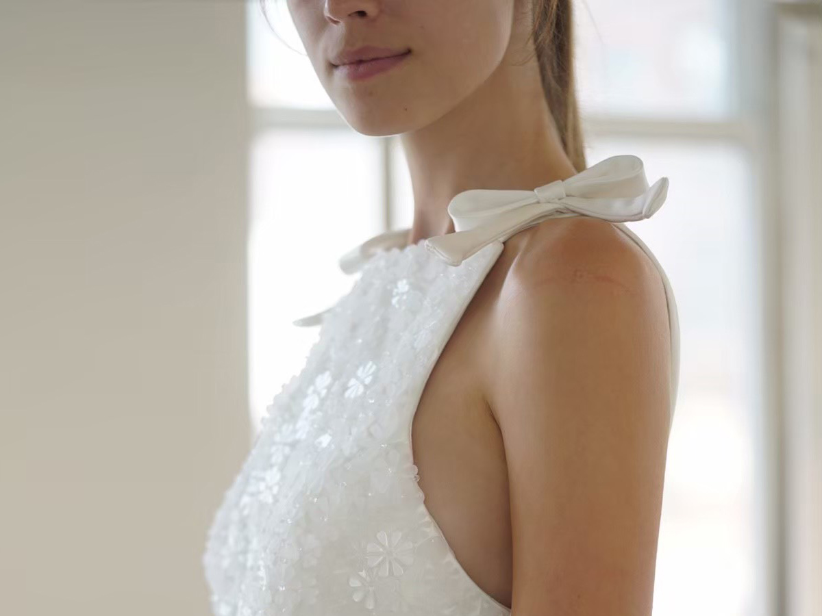 肩に白いリボンが付いている合成樹脂を使ったフラワーモチーフの白いウェディングドレスはヴィクター＆ロルフ・マリアージュのドレス