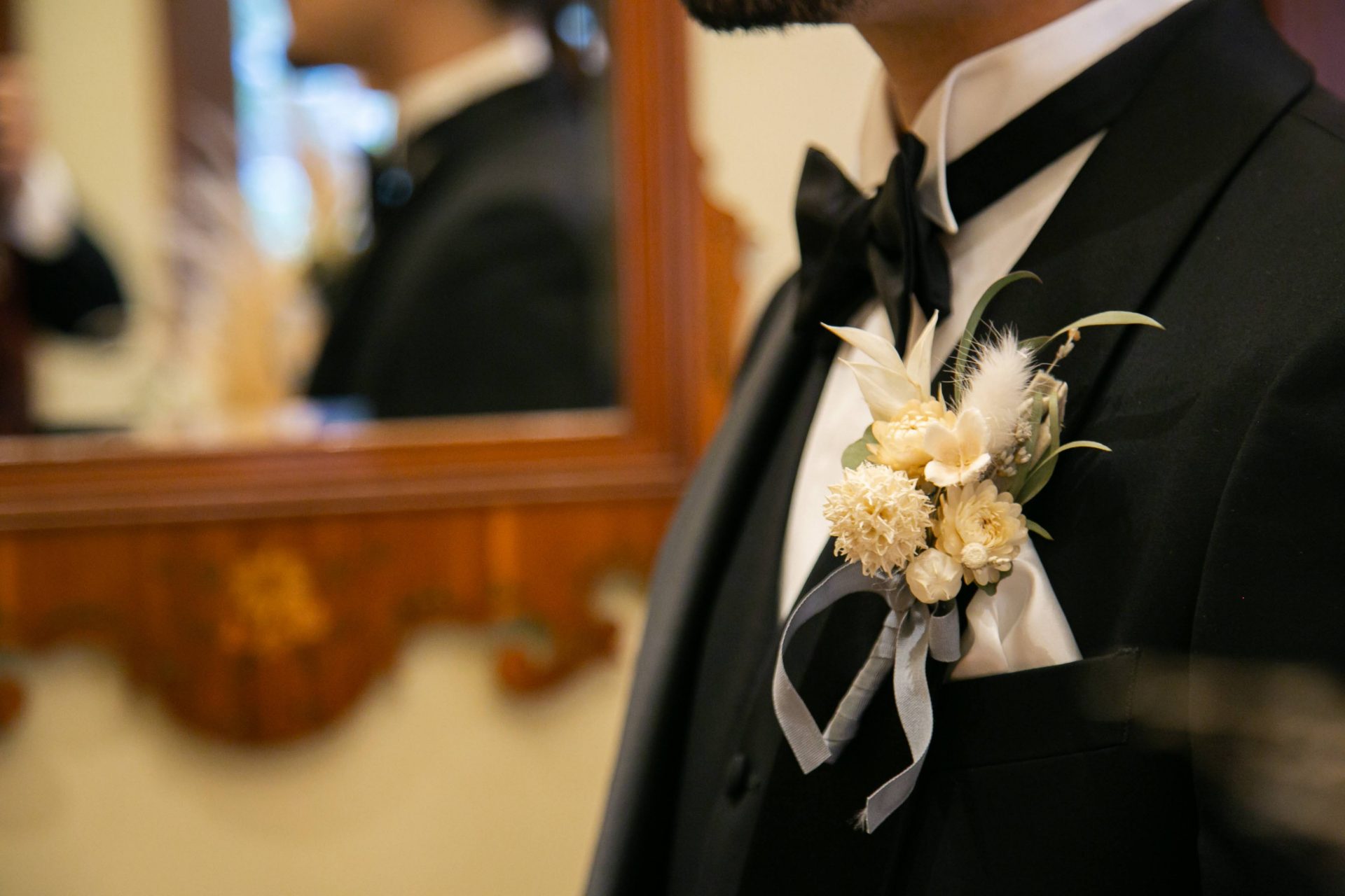 フォーマルでオーセンティックなブラックタキシードの胸元には、冬の結婚式に合わせホワイトやアイボリーで統一されたブートニアが華やかに映えます