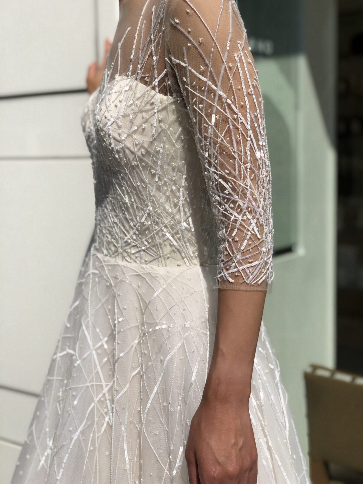 スパンコールで刺繍された直線に不規則にビーズが降りかけられたようにちりばめられたゴージャスなレンタルウェディングドレスで前撮りを楽しまれてはいかかでしょうか。