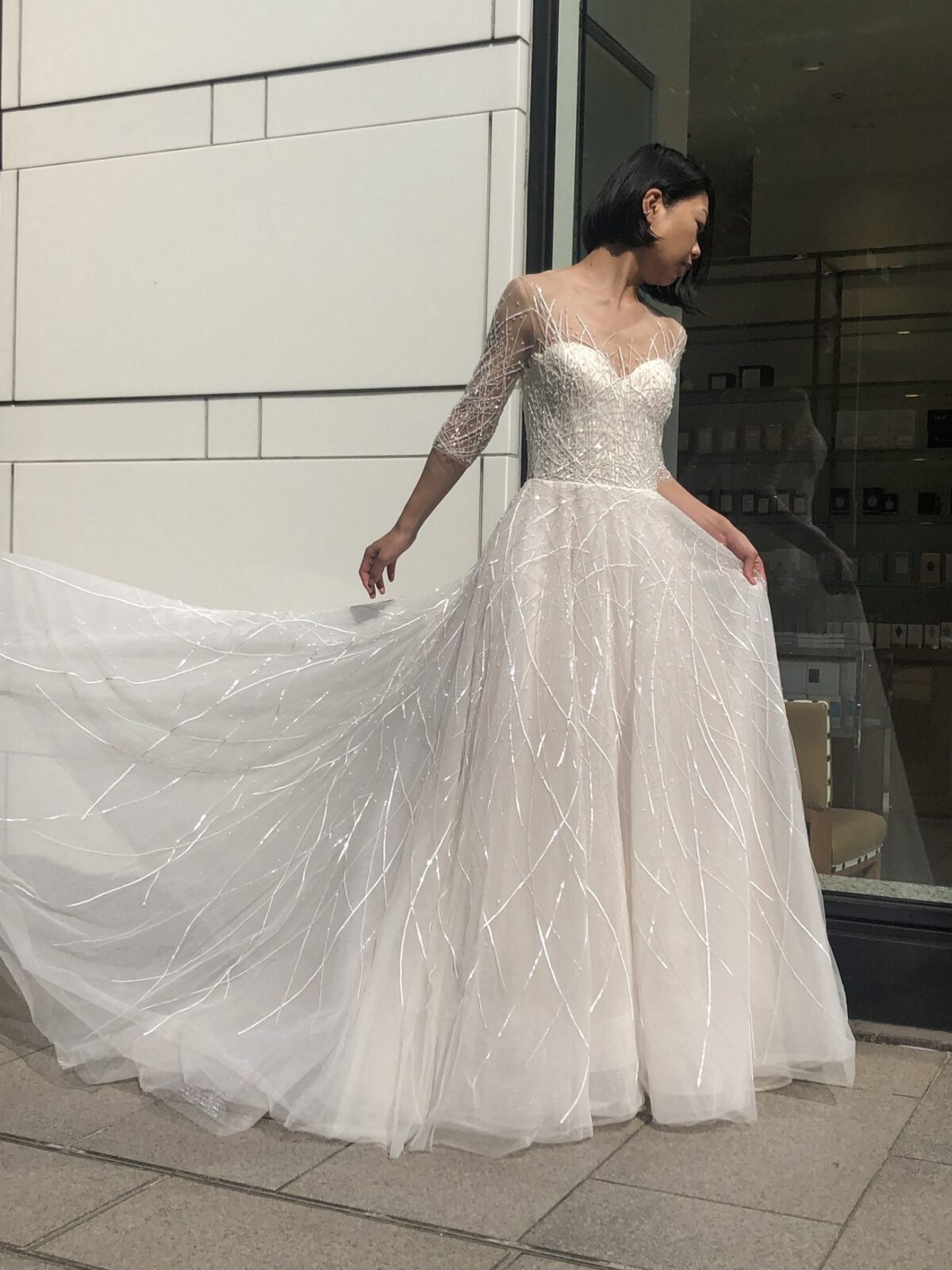 バーニーズニューヨーク横浜店で人気のレンタルウェディングドレスは直線状にビジューが施され、屋外では特にきらきらと美しく輝くハーフスリーブのAラインドレスです。