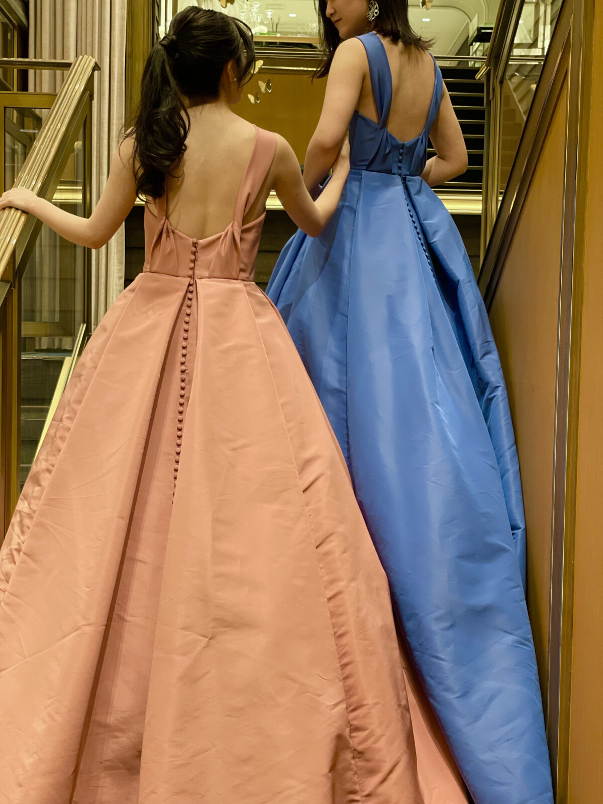 バックスタイルにくるみボタンが施された色違いのピンクとブルーのふんわりと広がるAラインカラードレス