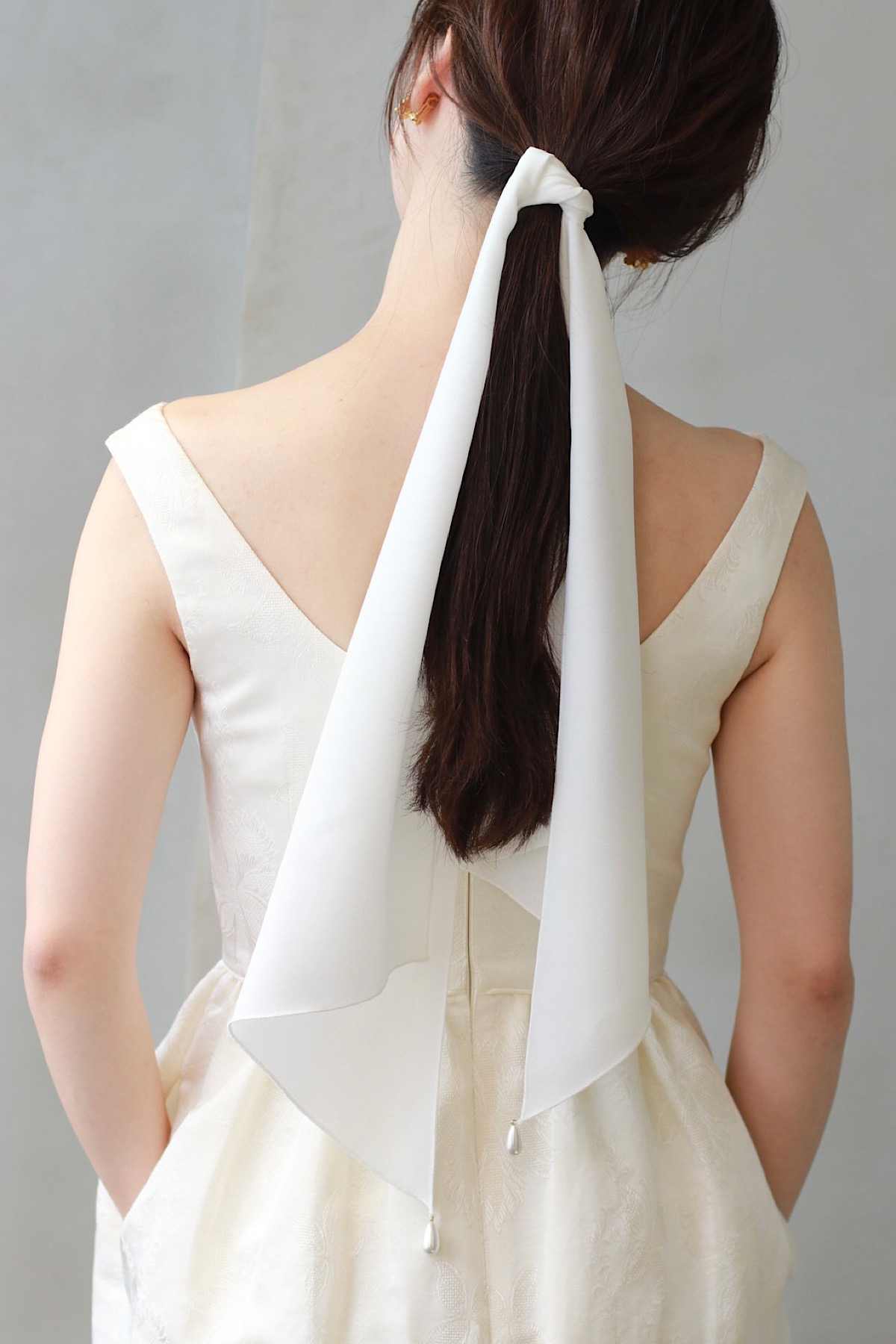 アットホームな結婚式にご提案したいバックスタイルはクレープ素材のスカーフがローポニーテールに結ばれて、エフォートレスでありながら特別感のあるコーディネート