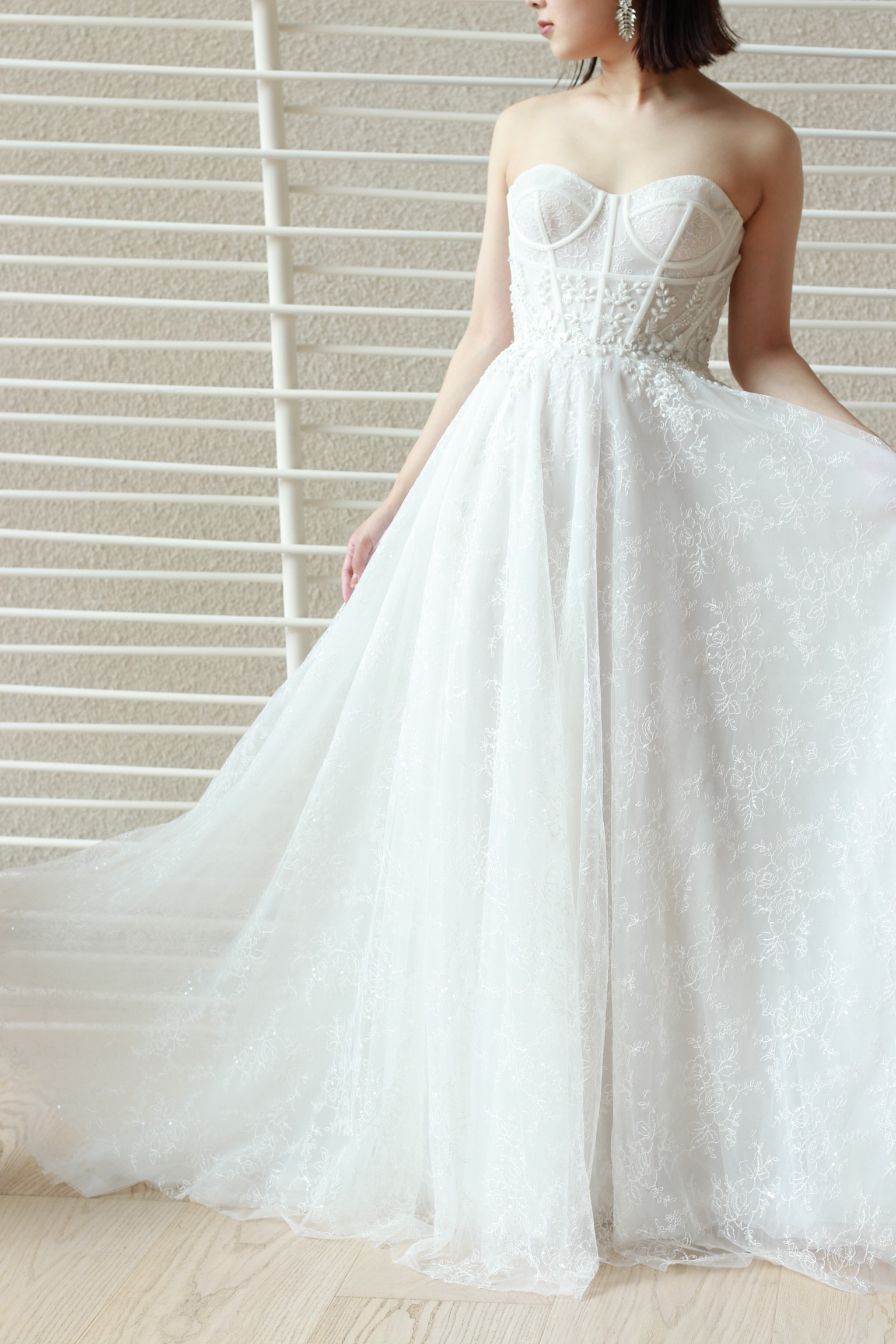 Aラインのウェディングドレスはいつの時代も花嫁に愛される美しいシルエットです。そのラインにトレンド感溢れるリズマルチネスの装飾を施すことでおしゃれな印象を表現できます。