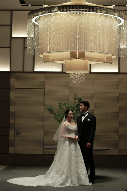 フォーシーズンズホテル東京大手町で王道な結婚式を叶えるトリートのブラックのタキシードとモニークルイリエの総レース・Aラインのウェディングドレスを身に纏った新郎新婦