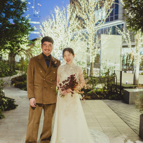 THE TREAT DRESSING の提携会場赤坂プリンスクラシックの外観にて、お式後のお写真。 イルミネーションも相まってロマンティックな印象なお二人。