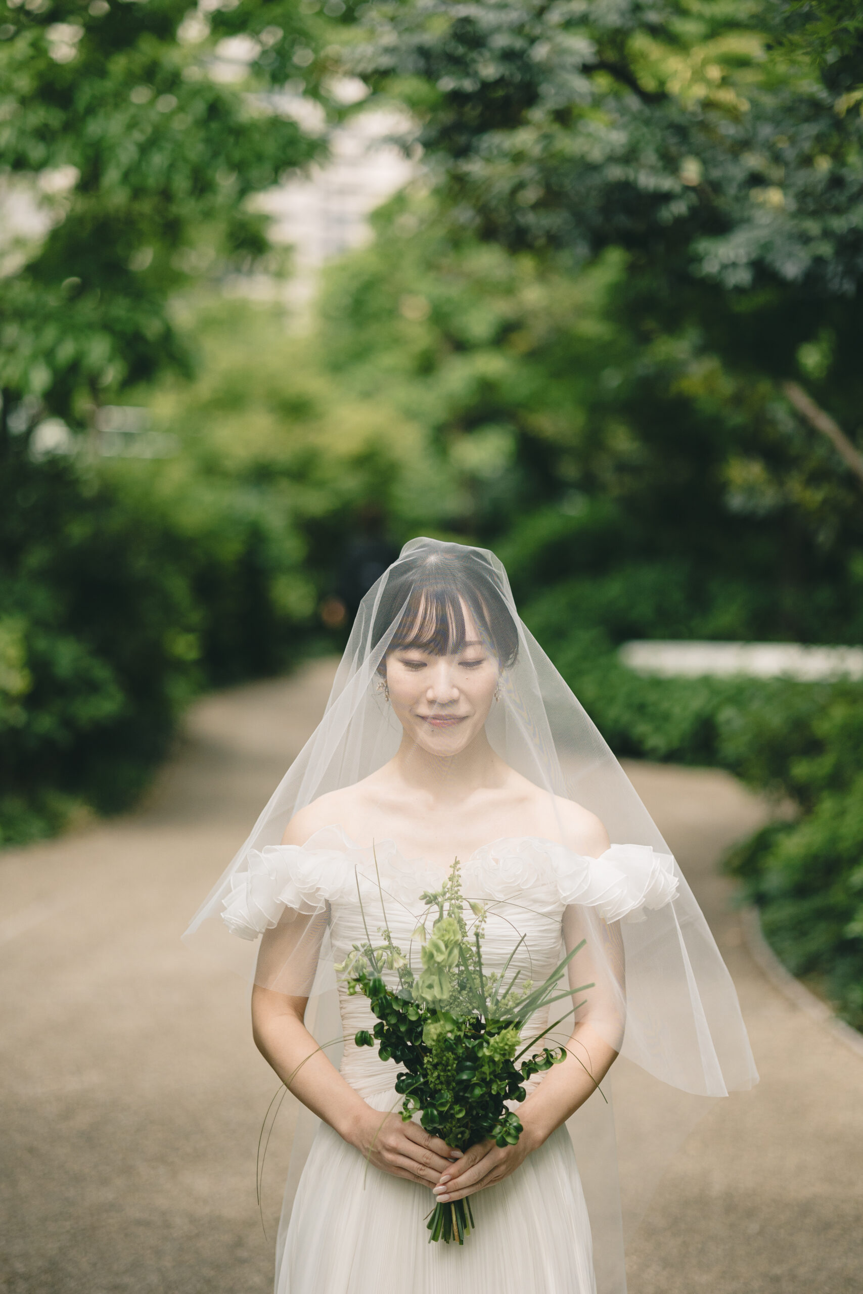 沢山の緑の中、トリートが扱うオートクチュールブランドのジャンバティスタヴァリのウェディングドレスを纏う上品なご新婦様。