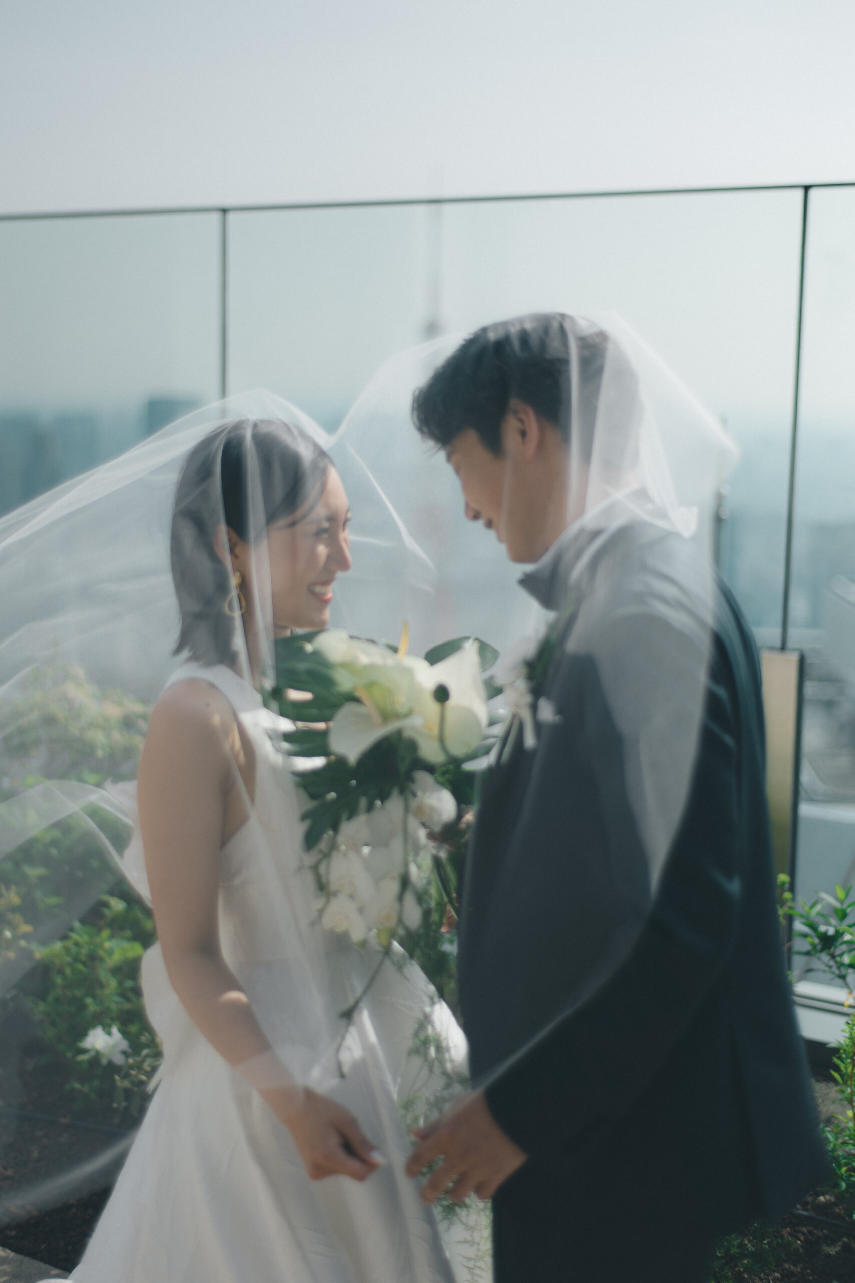 東京タワーをのぞむアンダーズ東京のテラスで、柔らかなベールに包まれお写真撮影をされるご新郎ご新婦様