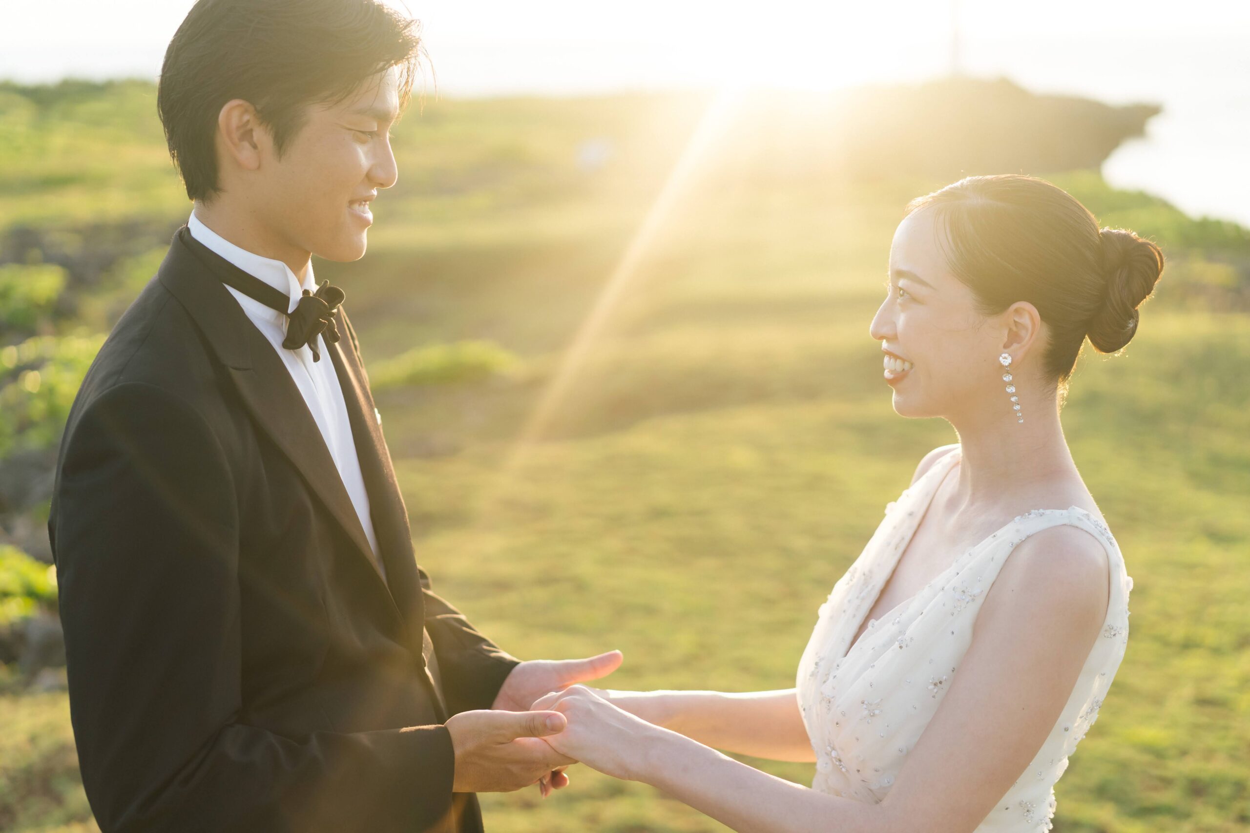 沖縄のサンセットを背景にトリートのドレスとタキシードを着用した新郎新婦のトリート沖縄店のフォトウェディング