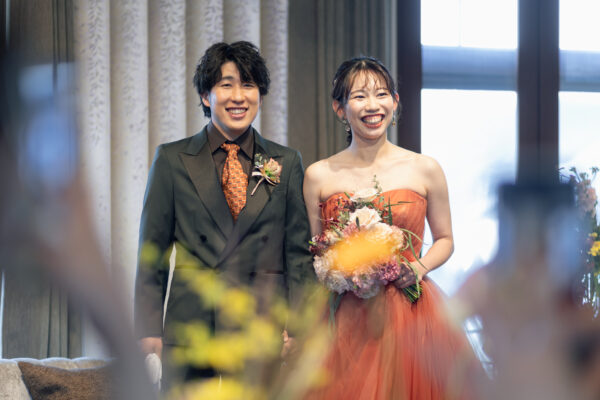 オリーブ色のタキシードとテラコッタカラーのカラードレス