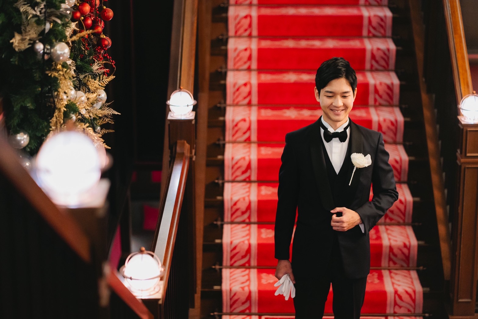 新郎様がお召になられたのはトリート ジェントルマンのブラックタキシード 赤の大階段が象徴のクラシカルな会場に映える一着です